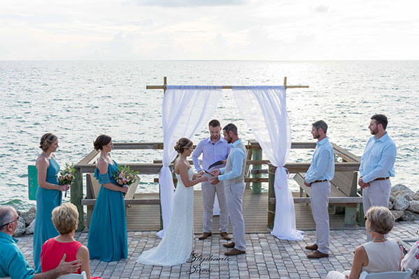 couple getting married under a beautiful arbor at a Manasota Key wedding ceremony