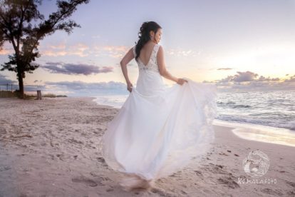 the back of the bride's gown on the beach at sunset