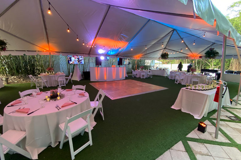 DJ booth with TVs in an outdoor tent, set up for a wedding reception at the Palm Island Resort