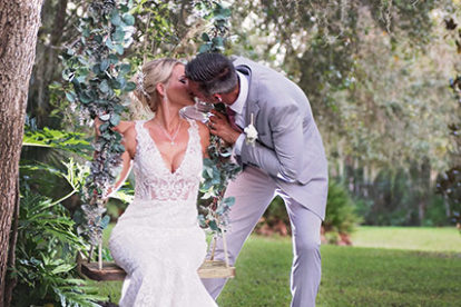 bride and groom kissing on a swing covered in vines