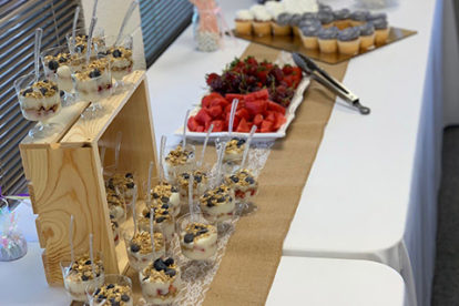 table with yogurt parfaits, donut holes, fruit and cake