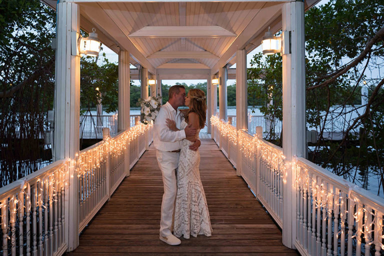 Bride and groom kissing on a lighted bridge