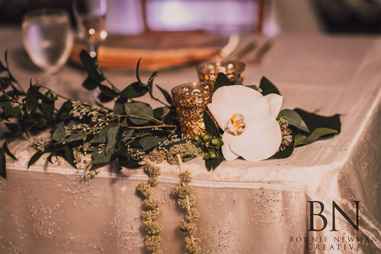 gold votive candles with orchids at a wedding reception