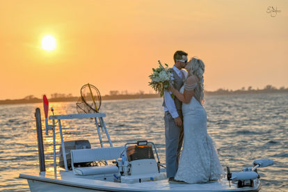 bride and groom standing on a small boat at sunset in Florida