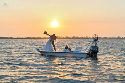 bride and groom standing on a small boat in the Intracoastal in Englewood, FL at sunset