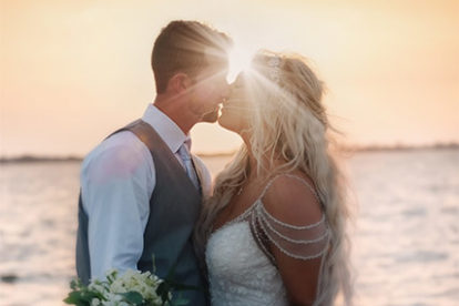 dramatic photo of a bride and groom kissing at sunset