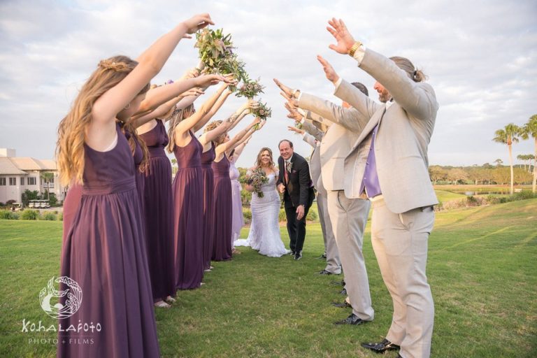 bridal party using their arms to make a tunnel for the bride and groom