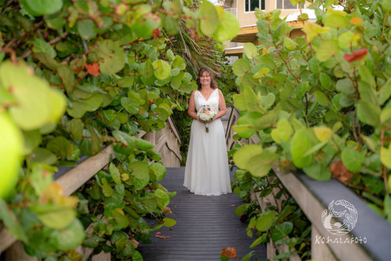 bride walking down a boardwalk surrounded by seagrape trees