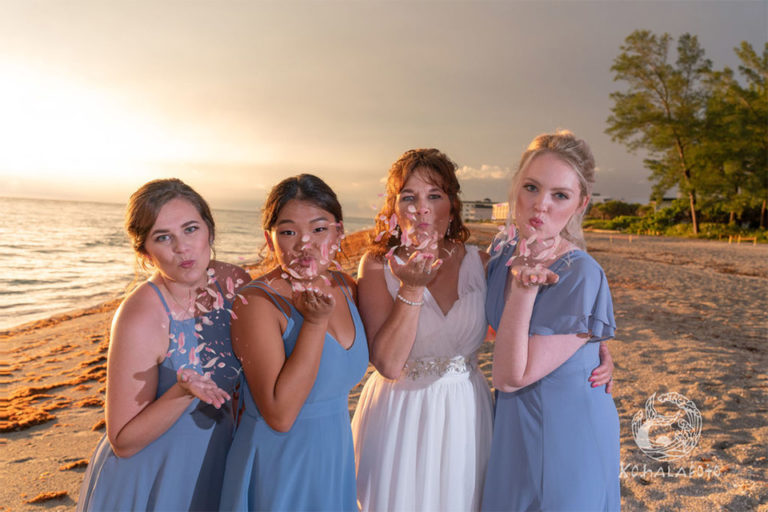 bride and bridesmaids blowing petals on a beach in Englewood FL