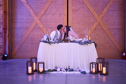 bride and groom kissing at the sweetheart table at their wedding reception