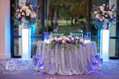 sweetheart table designed by a Florida wedding planner in Orlando with silver tablecloth and white and blue flowers