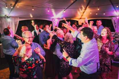 wedding guests dancing in an outdoor tent reception