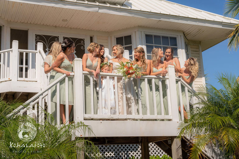 bride and bridesmaids leaning over the railing in front of a condo