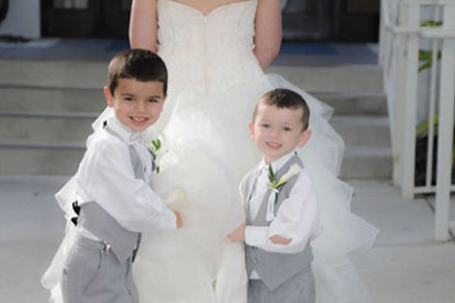 two young boys holding the train of the bride's dress