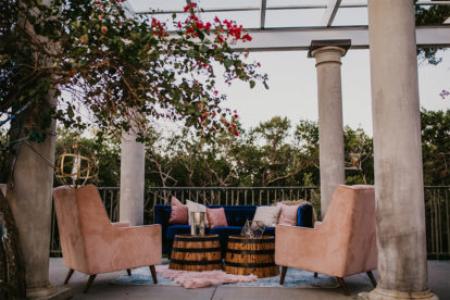 seating area in an outdoor pergola with pink accent chairs and a blue sofa