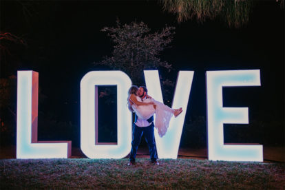 bride and groom kissing in front of large letters spelling LOVE