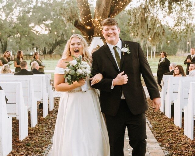 bride and groom laughing while walking up the aisle after an outdoor ceremony in Seffner, FL