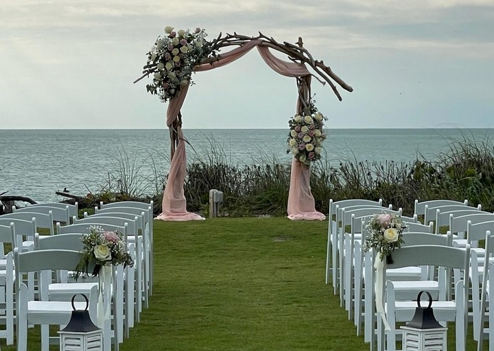 close up of chairs and arbor set up for a wedding ceremony on a lawn near the beach in Boca Grande Florida