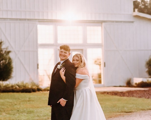 bride and groom posing outside a white barn in Seffner, FL