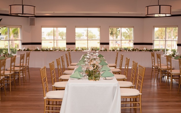 decorated tables with gold chairs at a wedding reception