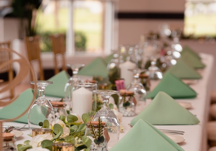 table decorated for a wedding with flower arrangements, mint green napkins, and gold accents