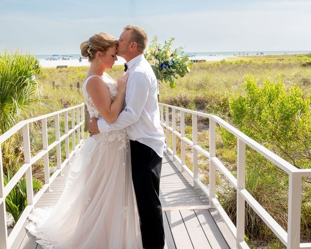 bride and groom nuzzling foreheads, standing on a boardwalk to Siesta Key Beach