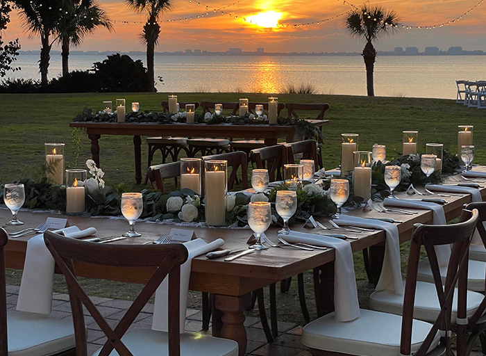 outdoor wedding reception table with the sun setting over the water in the background